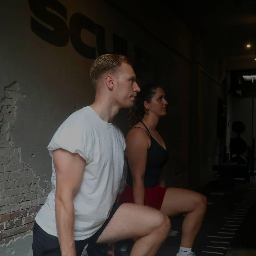Personal trainer coaching a client through a dumbbell shoulder press in the SculptClub studio