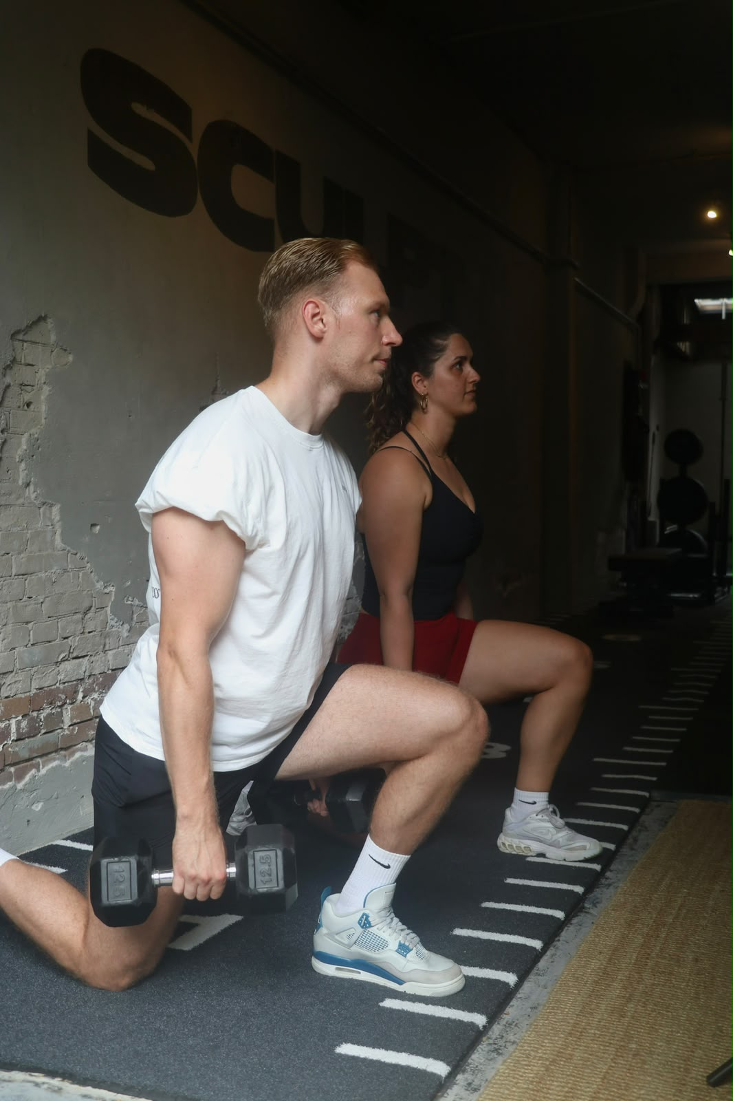 Twee sporters trainen samen met dumbbells in de privé studio van SculptClub in de Jordaan