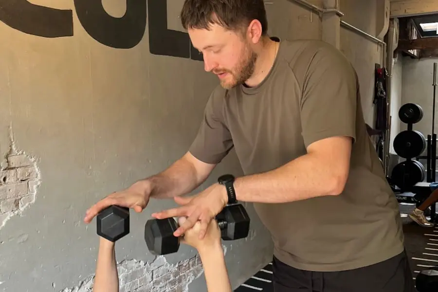 Dara begeleidt een dumbbell-oefening in de sportschool
