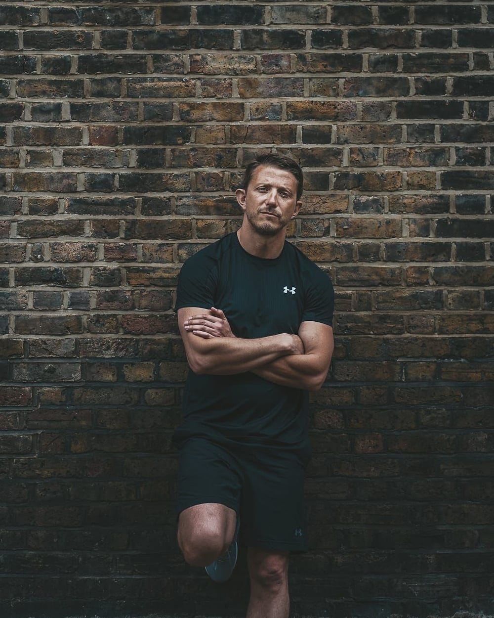 Tom, personal trainer at SculptClub, against a brick wall
